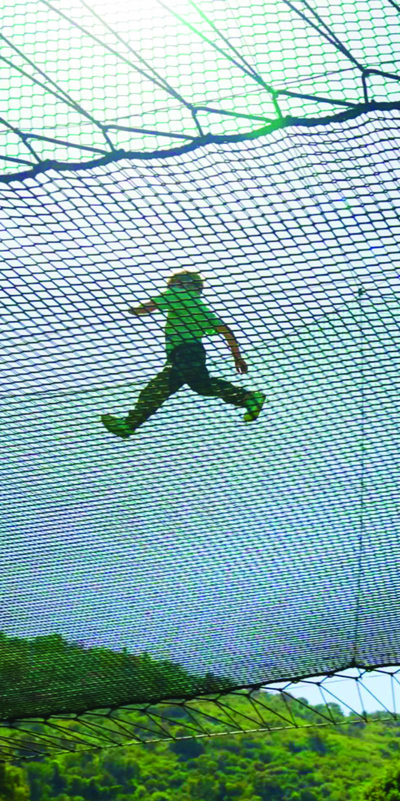 Child leaping across the netting of the Skynet Playground, seen from below