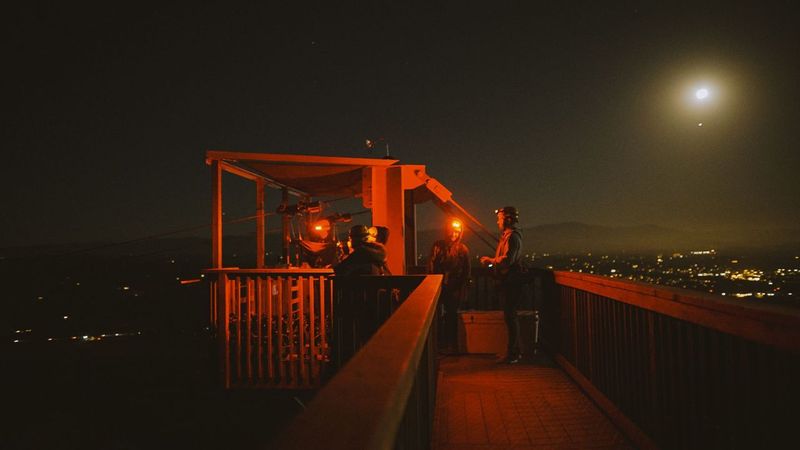 Guides and guests on the lit launch platform at night before a moonlight zip