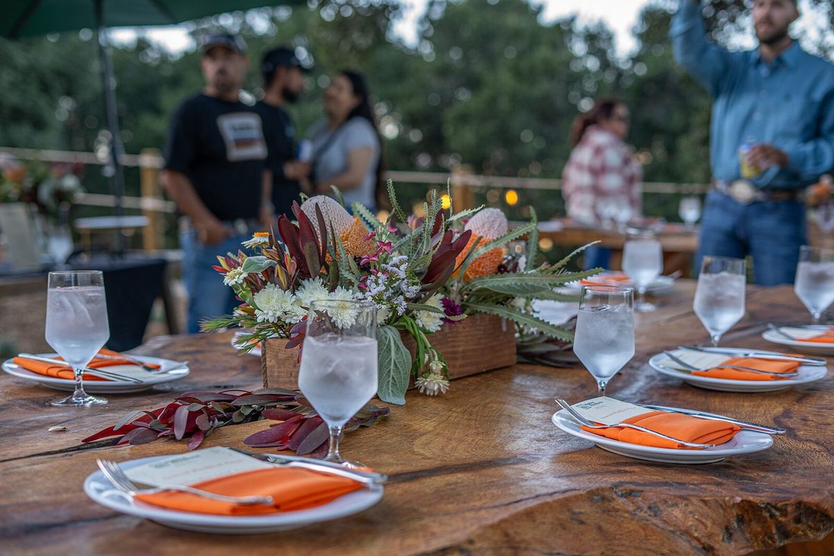 A long table set for a catered dinner at base camp, with Protea arrangements and the hills behind.