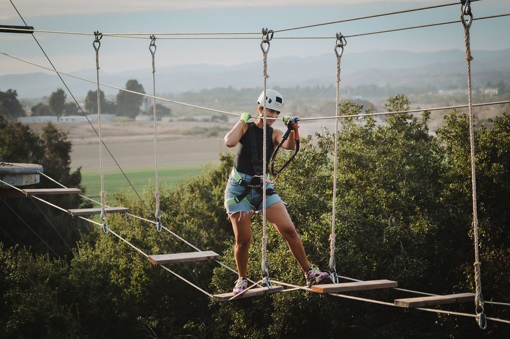 Guest crossing a rope bridge on the treetop Adventure Course above the Santa Ynez Valley