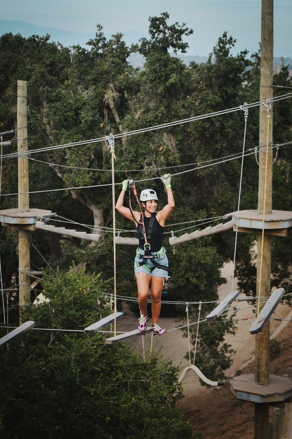 Girl climbing a net element of the Adventure Park ropes course in a harness