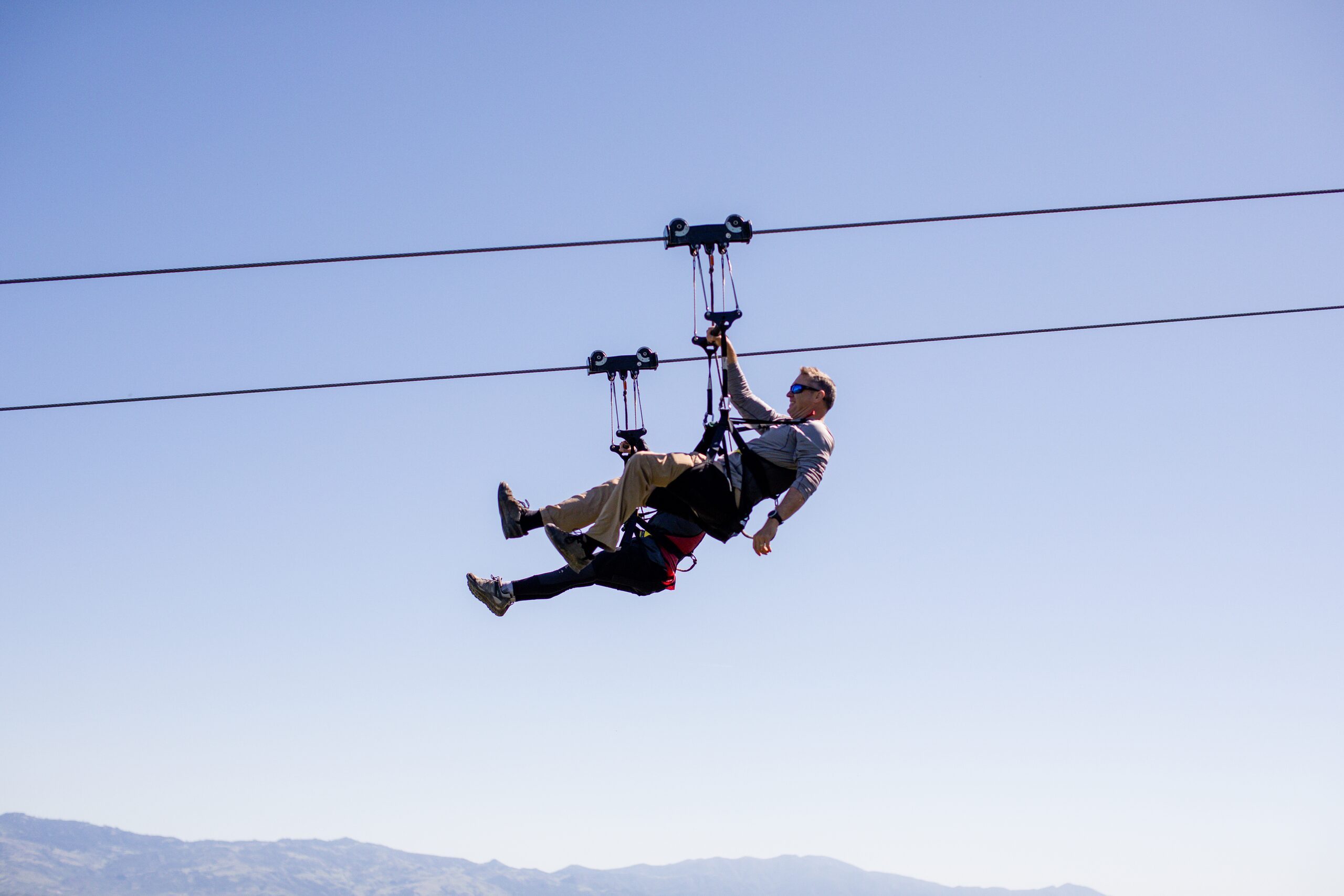 Zipliner mid-flight in harness and helmet above the Santa Ynez Valley