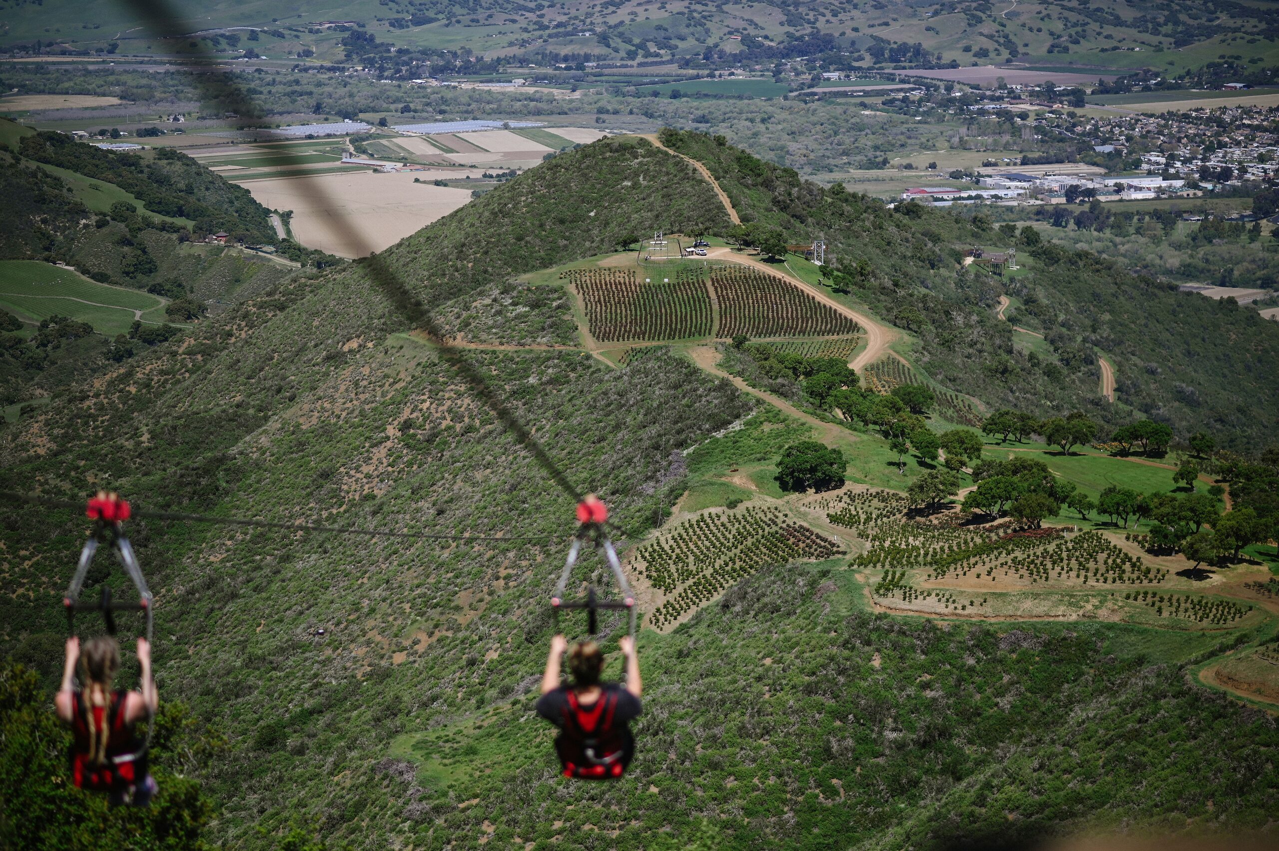 Two riders on the dual ziplines high above the Santa Ynez Valley