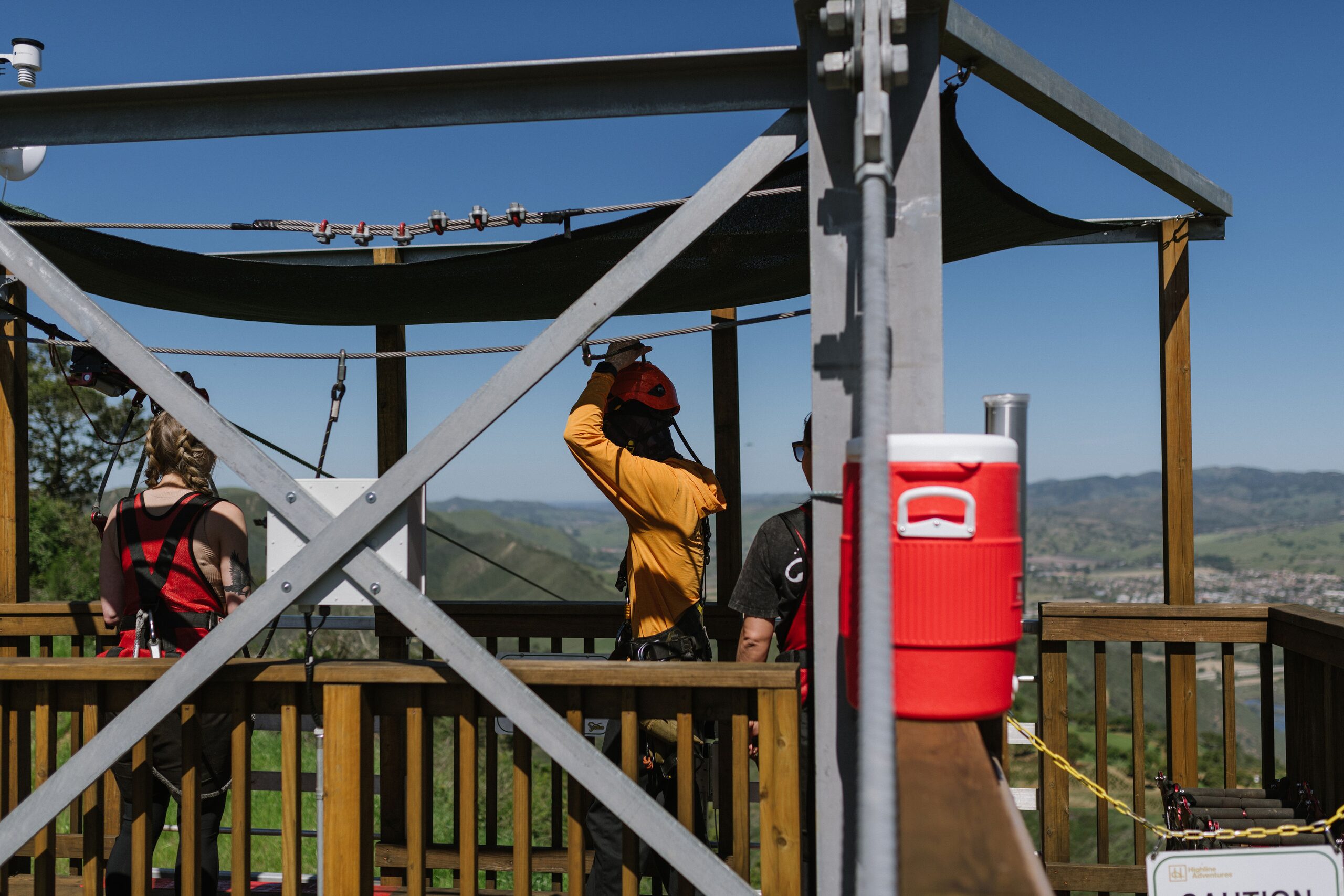 Highline Adventures guide checking a rider's harness and connections at the launch platform before the first zip