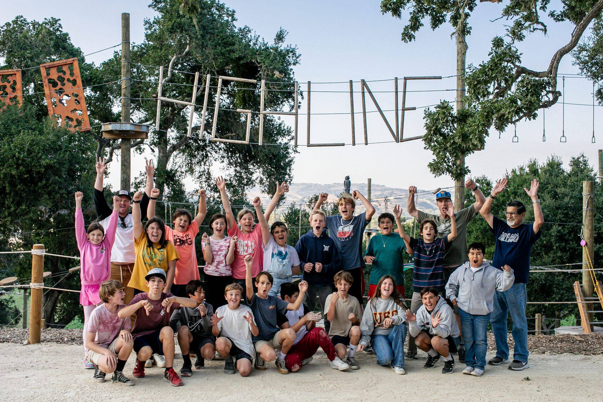 A school group posing together beneath the Highline sign after their Adventure Park session.