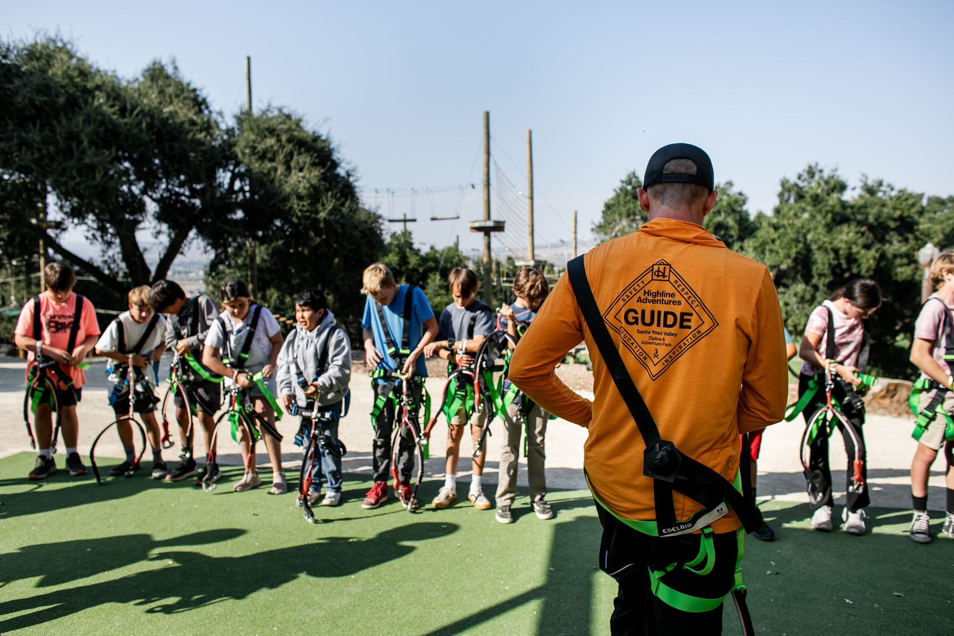 A Highline guide briefing a school group in harnesses and helmets before their Adventure Park session.