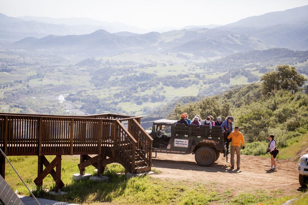 A group gathered at the summit zipline platform beside the 4x4 Humvee that brought them up.