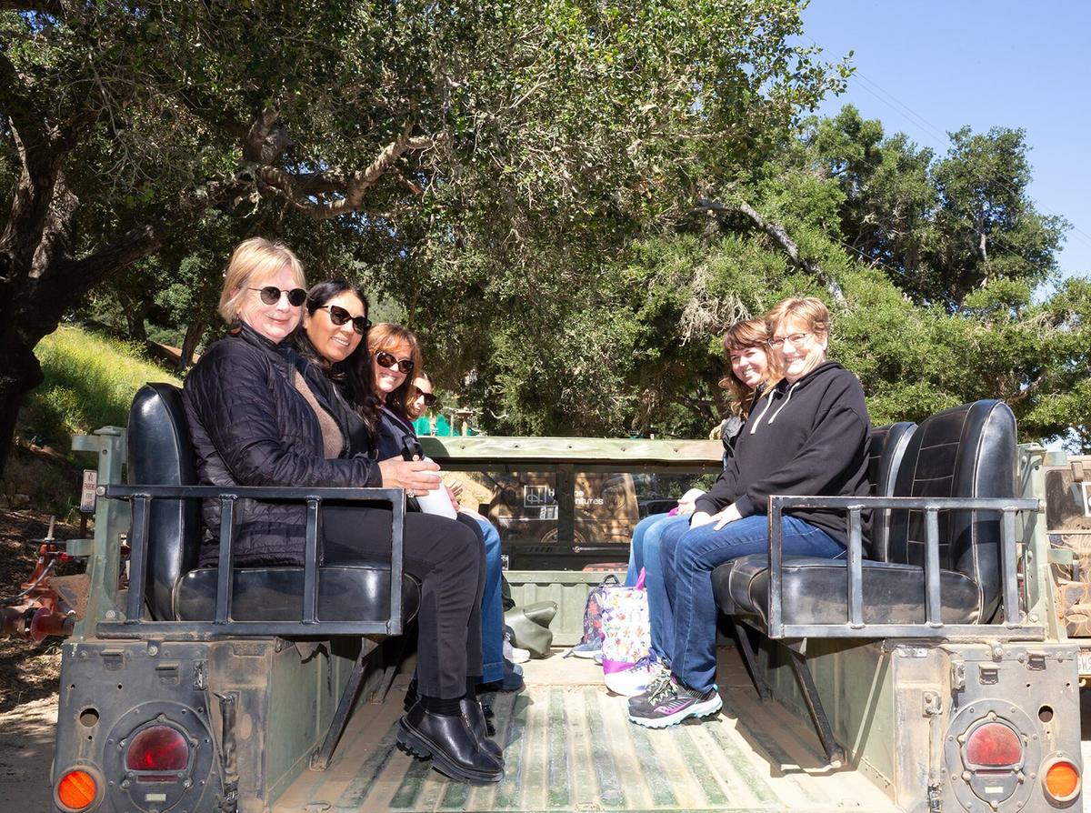A group of guests riding in the open-air 4x4 Humvee on the ranch road up to the zipline summit.