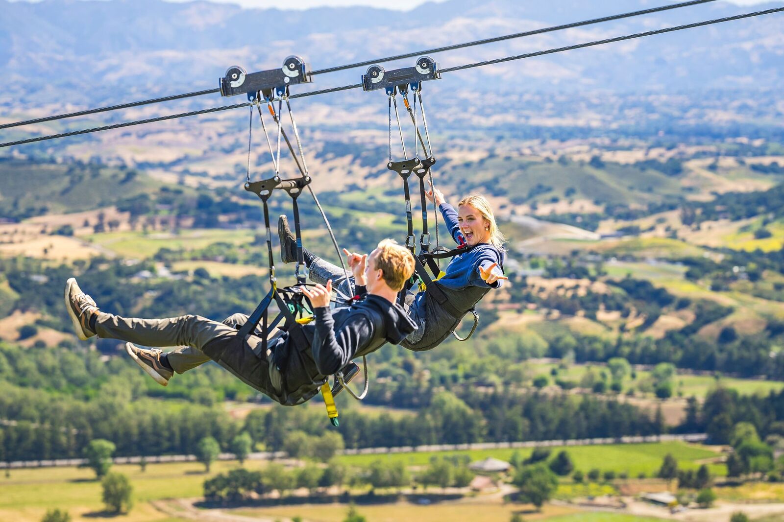 A zipline rider flying over the green hills of the Santa Ynez Valley on a birthday zipline tour near Santa Barbara.