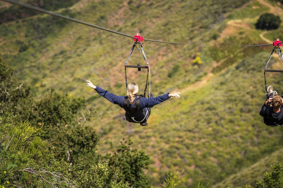 Two guests launching from the zipline platform above the Santa Ynez Valley at Highline Adventures near Buellton.