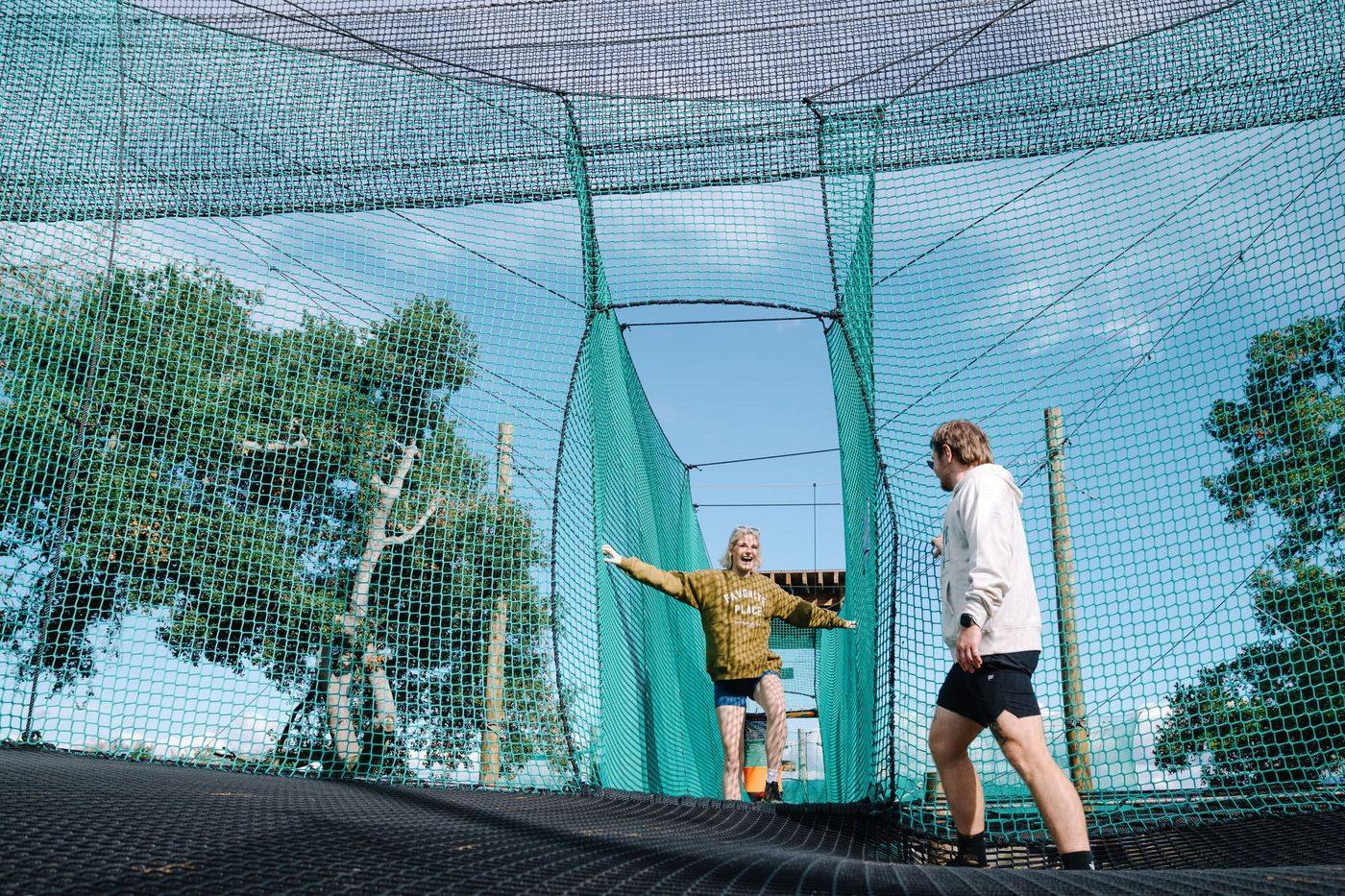 The suspended woven net of Skynet Playground strung high between oak trees.