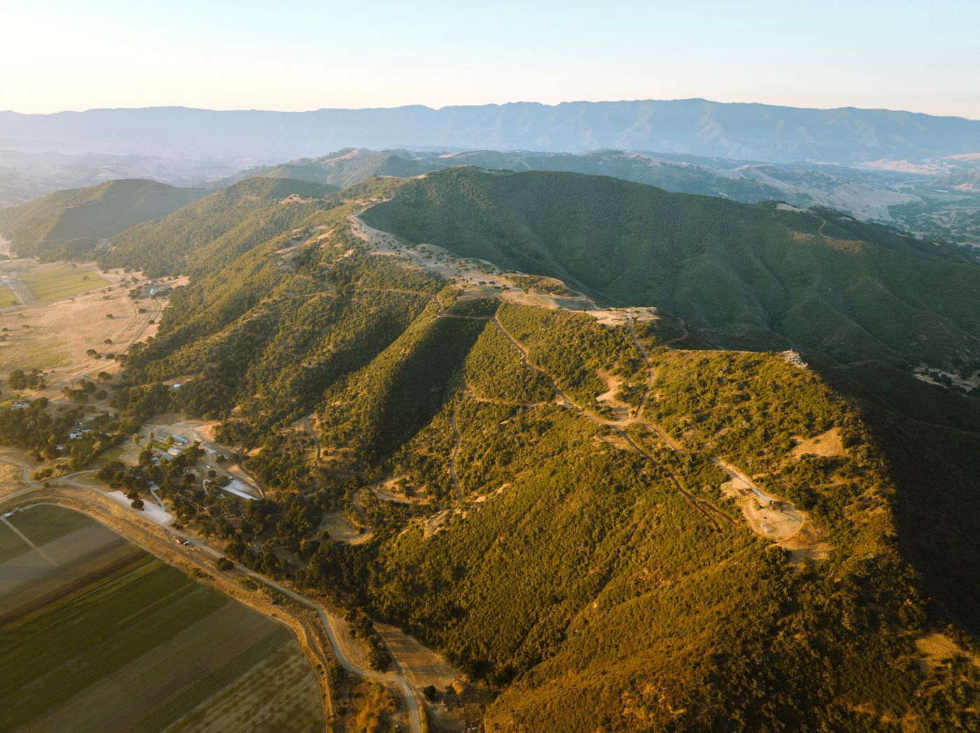 Aerial view of oak-covered hills above a patchwork of farm fields and vineyards in the Santa Ynez Valley.