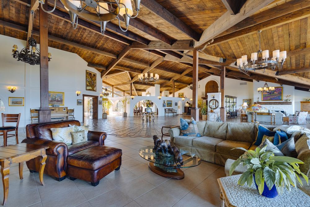 The Summit House grand room, timber ceiling, stone fireplace and windows to the valley.