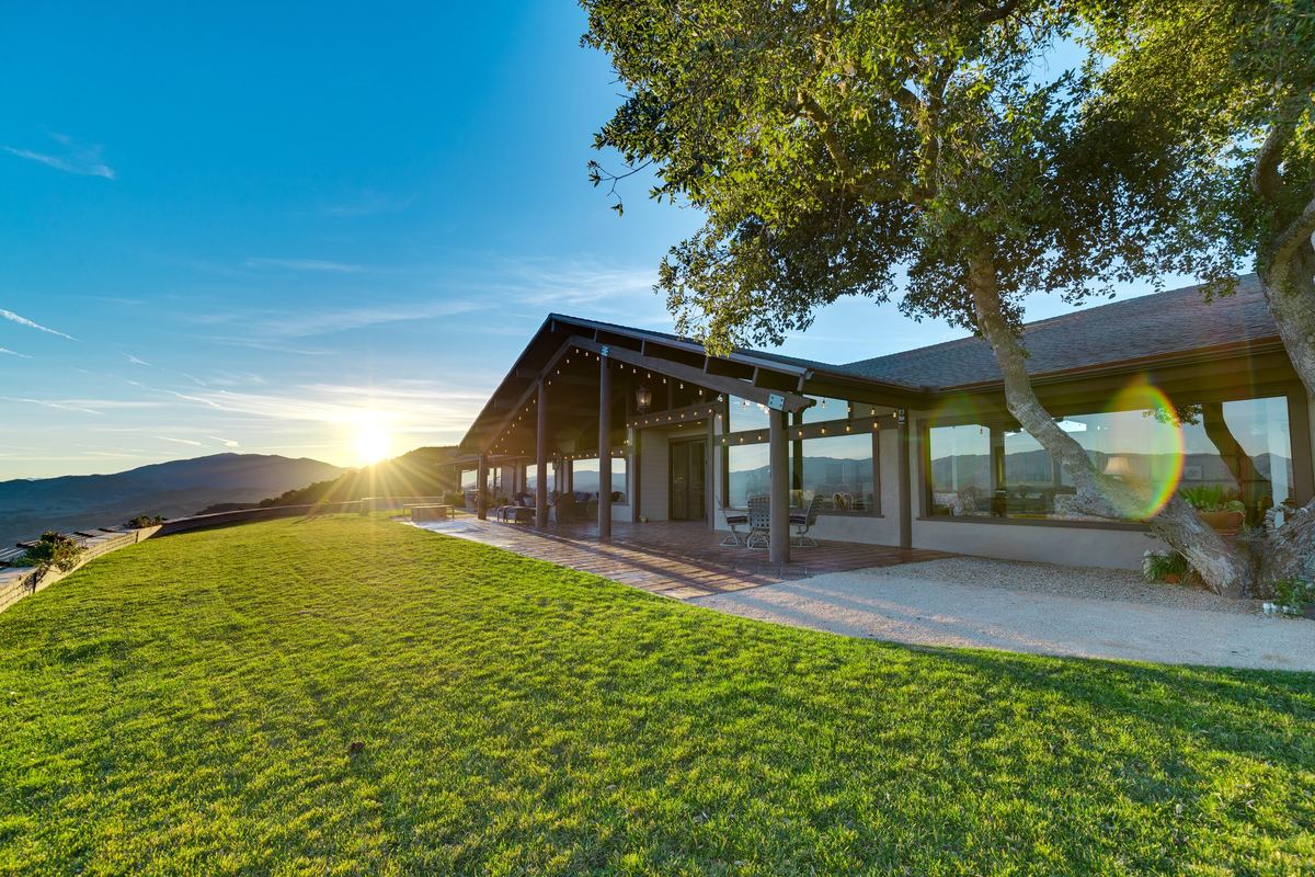 The Summit House lawn at sunset, the house's glass front catching the last light.